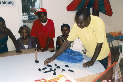 A man arranging twelve carved keyrings on a table