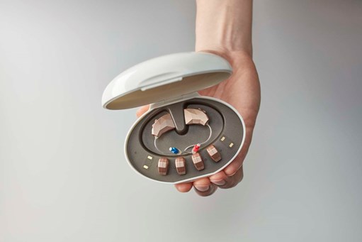 hand holding hearing aids in a case