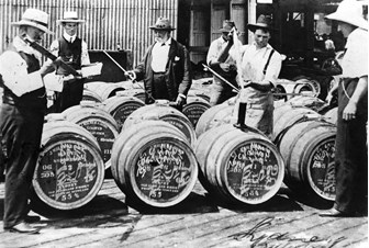 Men measuring large kegs for alcohol content