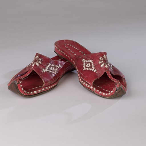 A pair of red and white leather shoes, a souvenir from a ship voyage, purchased in Port Said.