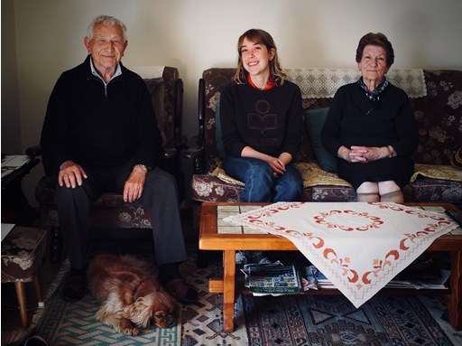 Ella Mittas sitting on couch with grandparents Dimitrios and Urania Mittas, with the family dog