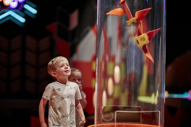 Young boy playing with suction tube exhibit in the Ground Up exhibition at Scienceworks