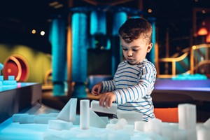 Boy playing with clear building blocks in the Ground Up exhibition 
