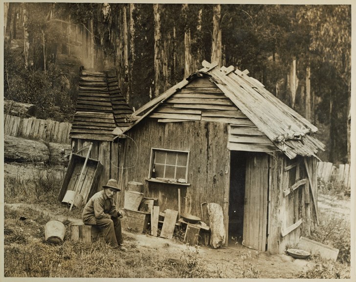 Man seated outside wood hut