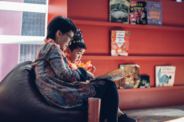 A mother and son are sitting in a beanbag reading a book