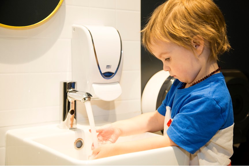 Boy washing his hands in the children's toilet inside Ground Up exhibition space.