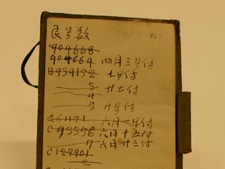 Rectangular note book with cardboard cover and tie. The pages have sums as well as writing in Chinese, English and Italian.