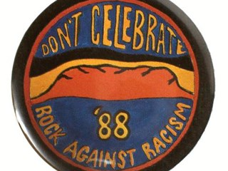 Round badge with a black background and an illustration of Uluru on it. It has two blue areas at the top and bottom of the image with yellow text on them: "Don't Celebrate '88: Rock Against Racism, Australia"
