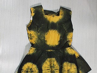 A sleeveless cotton dress with gored skirt, in green and gold tie-dyed pattern. The skirt has an additional, short layer attached at the waist.