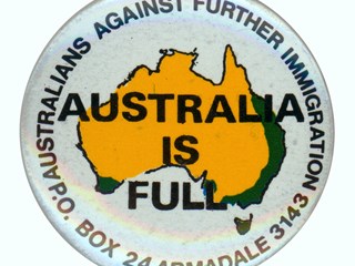 Badge - "Australia is Full, Australians Against Further Immigration", circa 1990. Circular button of metal alloy with safety pin fastener attached to the reverse. Front cover in fine layer of acetate beneath which is a layer of paper or motif and message have been printed directly on to metal base. White ground with map of Australia completed in yellow and green in centre.