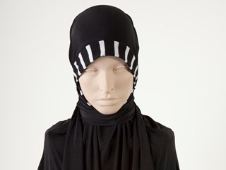 Black hijab made from lycra material with a black and white striped band around the head, neckline and at the bottom edge of the hijab. It represents the colours of the Collingwood AFL team. On the chestpiece is an iron-on Collingwood Football Club Logo of a black and white magpie, the Australian and black and white flags.