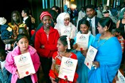 Several people of various ethnicities, with many brandishing their new citizenship certificates