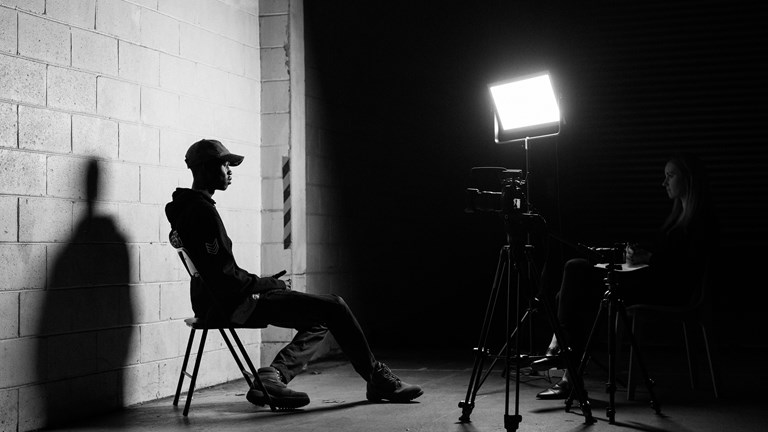 Black and white image of a person being interviewed on camera