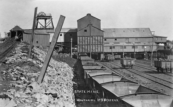Rail trucks at State Coal Mine, Wonthaggi, circa 1919. Poppet head and mine buildings in the background.