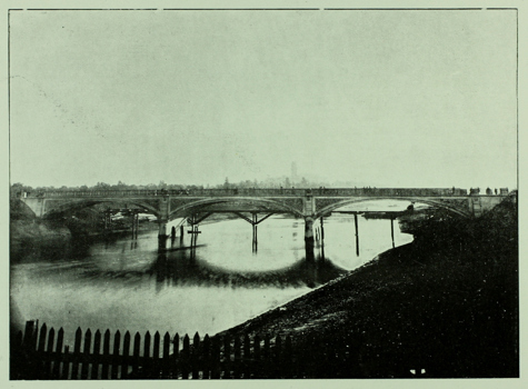 A bridge under construction spanning a river (the Yarra in Melbourne, circa 1899)