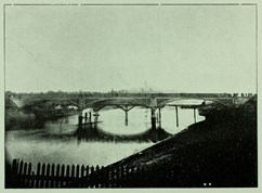 A bridge under construction spanning a river (the Yarra in Melbourne, circa 1899)