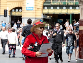 Woman wear a straw hat and read vest and jumper holding a clipboard