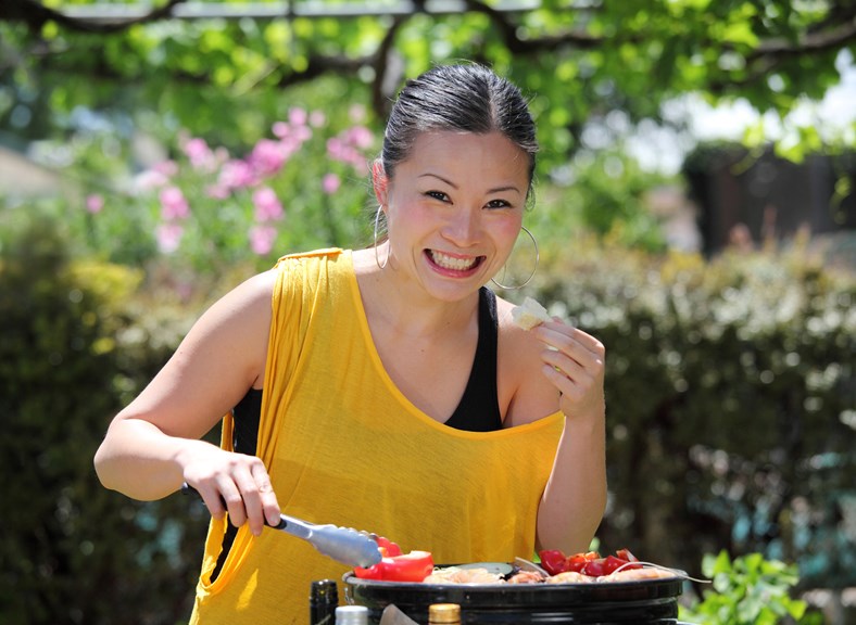 Asian woman cooking on a barbecue