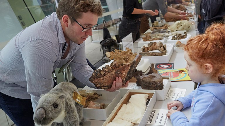 Museum staff showing fossils to a girl during Science on Show in Melbourne Museum.