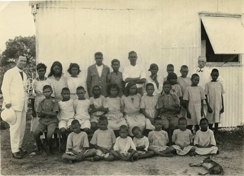 Black and white photograph of a group of Aboriginal children with 2 white men in suits