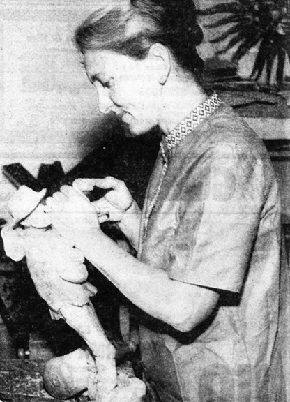 Black and white newspaper clipping of a woman carving wood