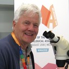 Man sitting in front of a microscope looking at the camera
