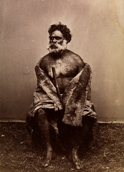 Portrait of a man wrapped in a possum skin cloak. 