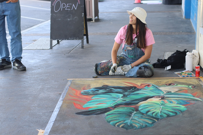 Tatiana Agudelo using chalk to make a mural on pavement.