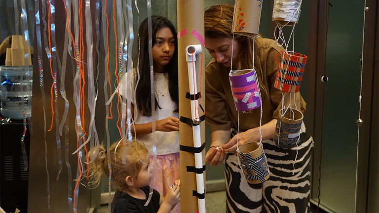 Children hanging art form the ceiling during a family art day.