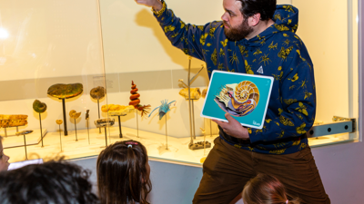 A Programs Officer shows children displays in the 600 Million Years exhibition.