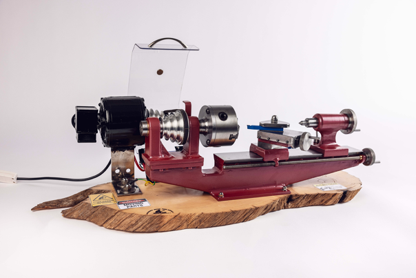Red-painted metal lathe set atop a slice of Huon pine.
