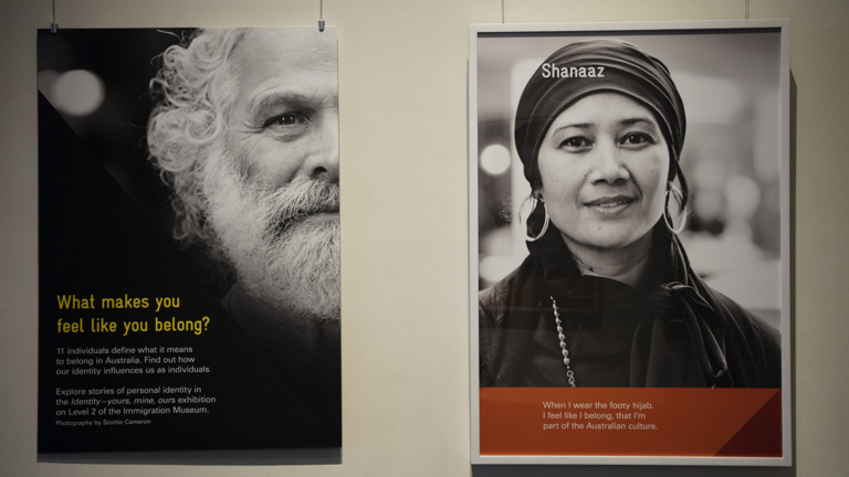 The faces of a bearded man and a woman wearing a head covering, hanging on boards suspended from the ceiling as part of the Identity: yours, mine, ours exhibition.