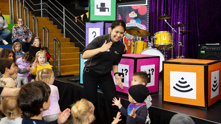 A presenter does the robot dance with children in the colourful Scienceworks outdoor amphitheatre.
