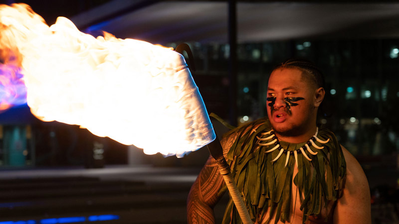 Logan Tapuala twirling fire outside Melbourne Museum.