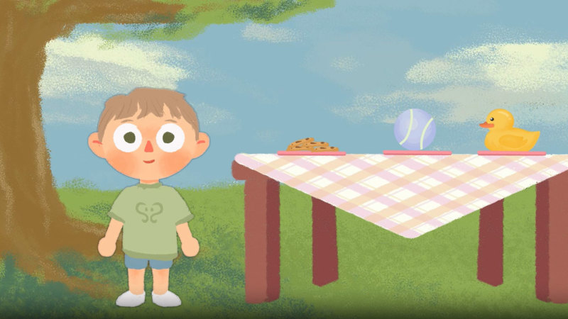 Animation still showing a small child in green T-shirt and shorts, standing in a park beside a picnic table with a gingham cloth, topped with plate of biscuits, ball, and rubber duck.