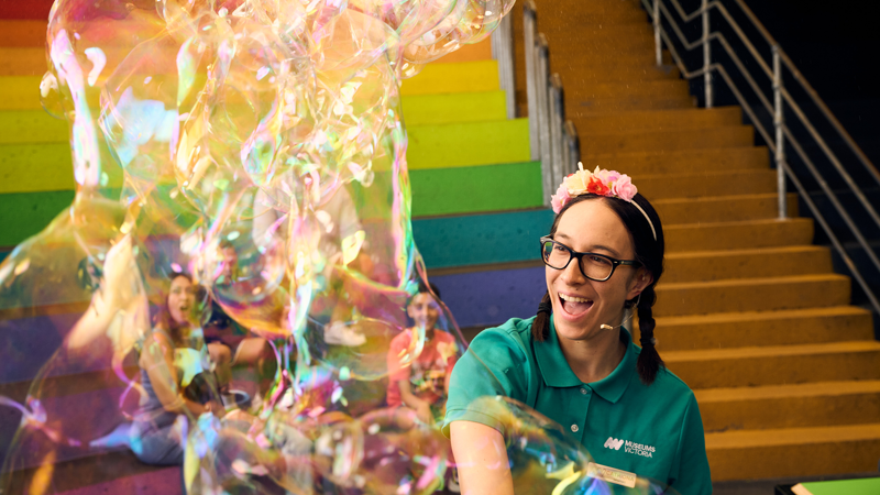 A presenter smiles while making bubbles in the Scienceworks Amphitheatre.