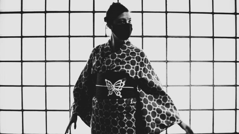  A black-and-white photograph of a person on kimono wearing a black medical mask.