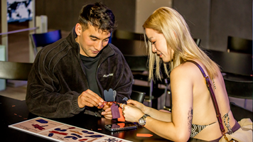 Man and woman making paper insects craft activity at a table. 