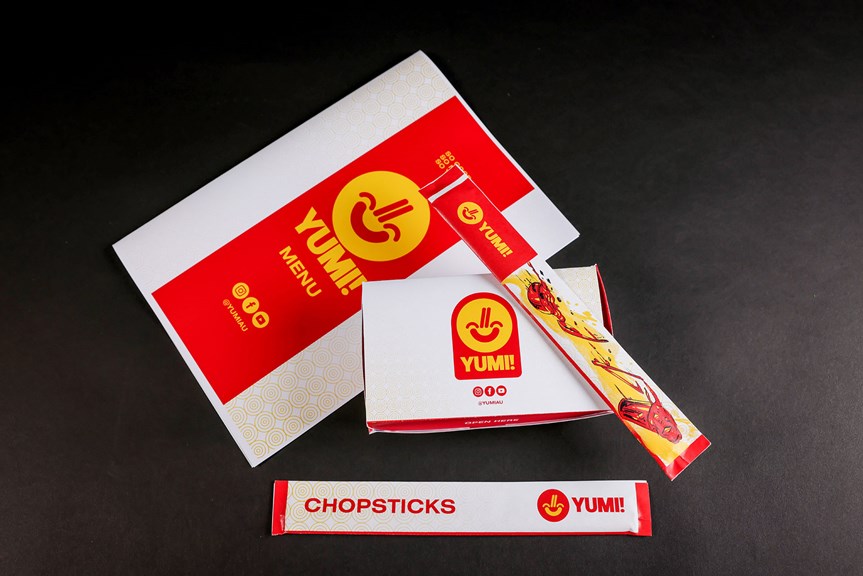 Menu, food and chopstick packaging, featuring red and yellow grapic design and 'Yumi Restaurant' branding.