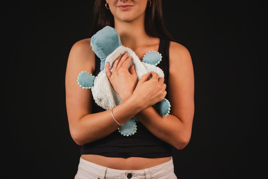 Person holding a stuffed toy turtle to their chest.