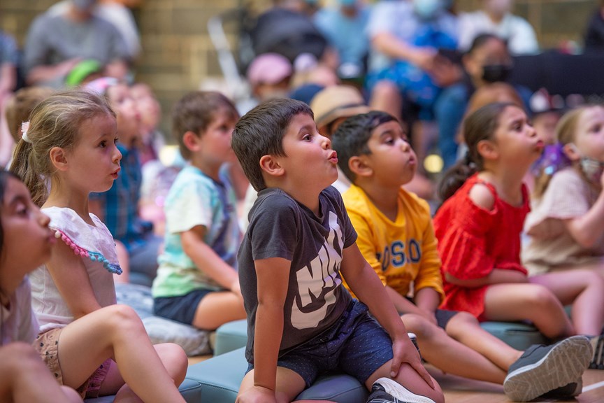 Children make fish mouths in reaction to a story being read to them at the State Library of Victoria.