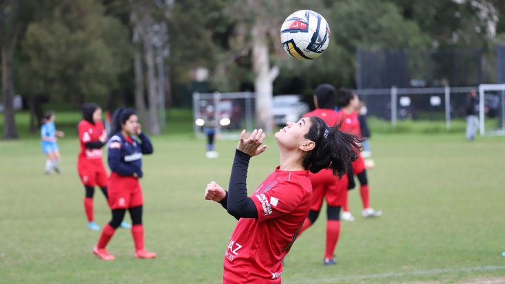 A woman bouncing a football above her head