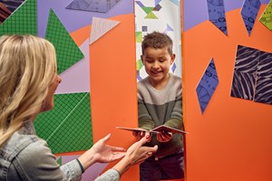 A parent and child solving a Tangram puzzle together.