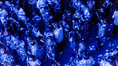 A birds eye view of people under blue light and dappled in disco ball lights.
