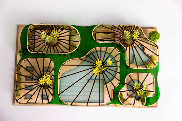Architectural model of a complex with curved wooden structures, green roofing, and rooftop plants.