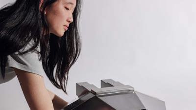 Metal model of an angular space shuttle with faceted silver-toned surfaces and geometric windscreen openings, mounted on a display stand.