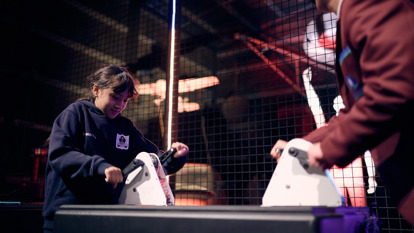 Two students race to produce the most energy using hand crank generators.