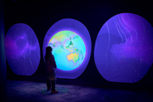 Person uses a display inside Our Wonderous Planet exhibition at Melbourne Museum.