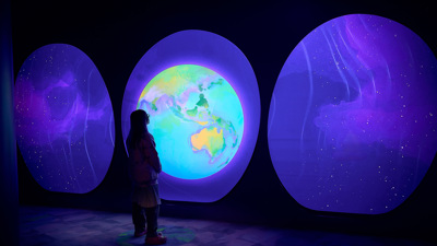 Person uses a display inside Our Wonderous Planet exhibition at Melbourne Museum.