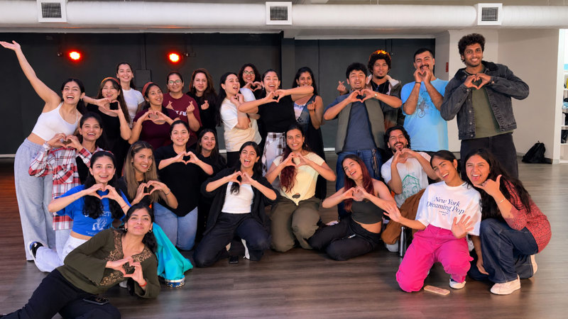  A group of Magan dancers posing, smiling at the camera and making heart shapes with their hands.